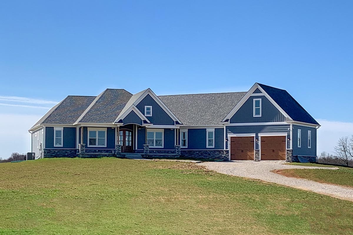 House plan exterior featuring a one-story, blue-sided house with multiple gables and a two-car garage. Features include a covered porch.