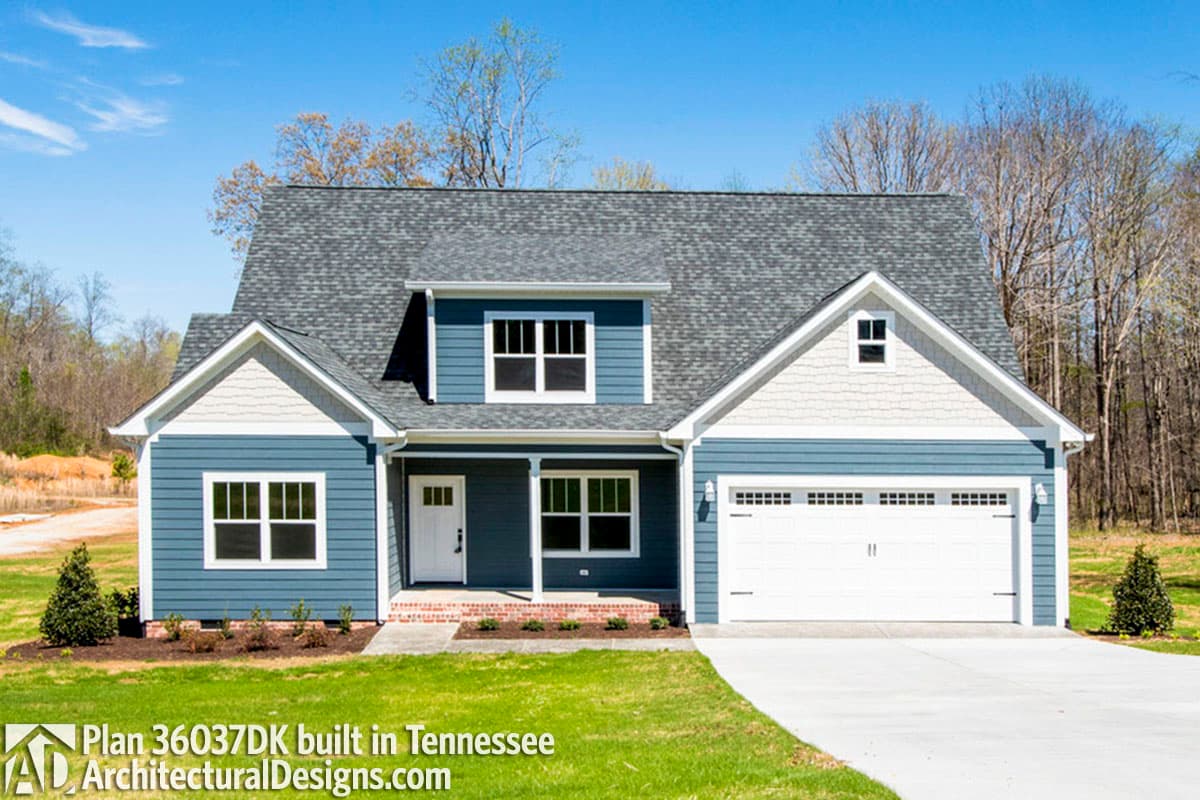 House plan exterior: Blue two-story home with white gables, covered entry porch, dormer, and attached two-car garage.