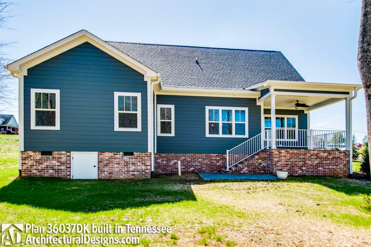 House plan exterior: Two-story home with blue siding, brick foundation, gabled roof, and covered porch with ceiling fan.