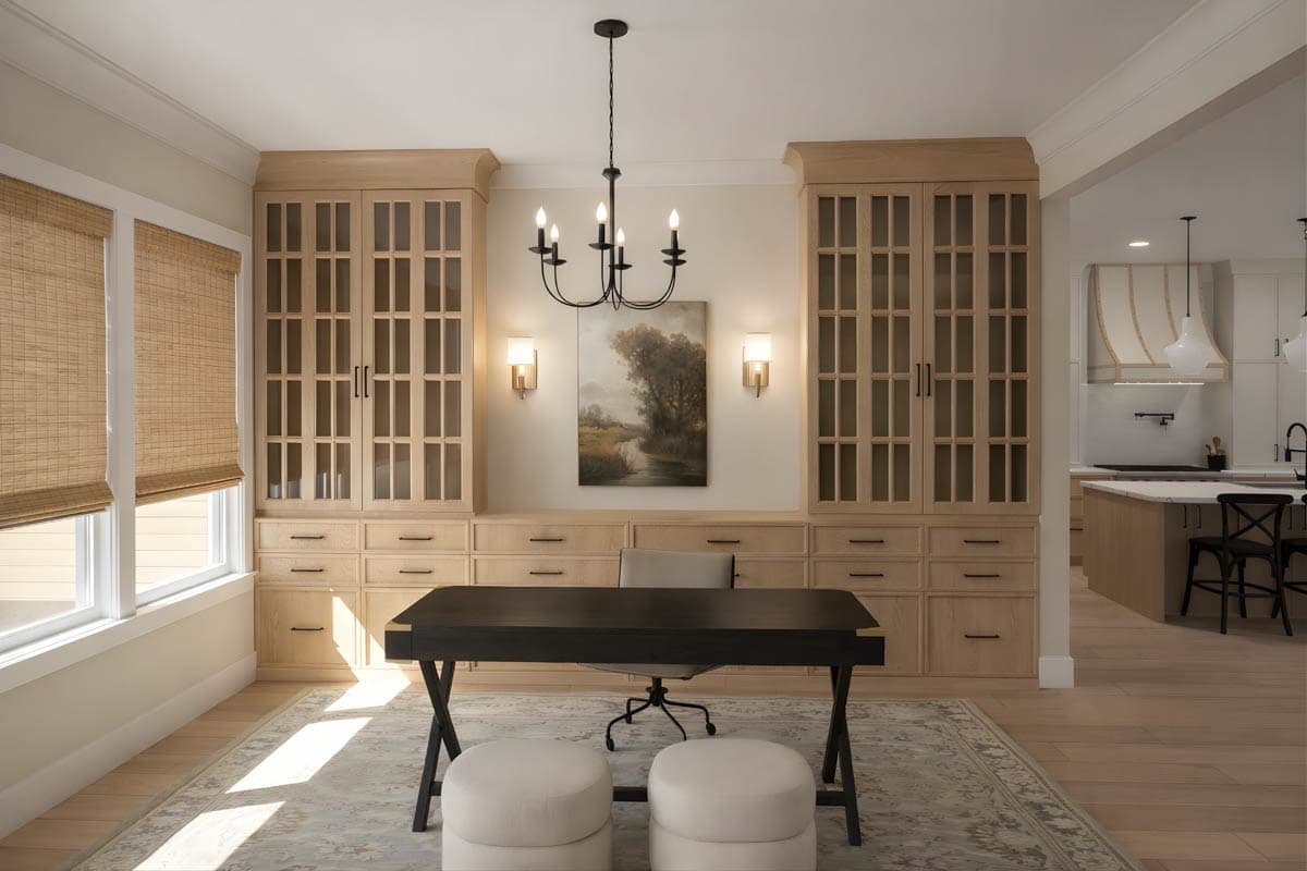 Home office with built-in light oak cabinets and drawers flanking a desk, plus a view of the kitchen.