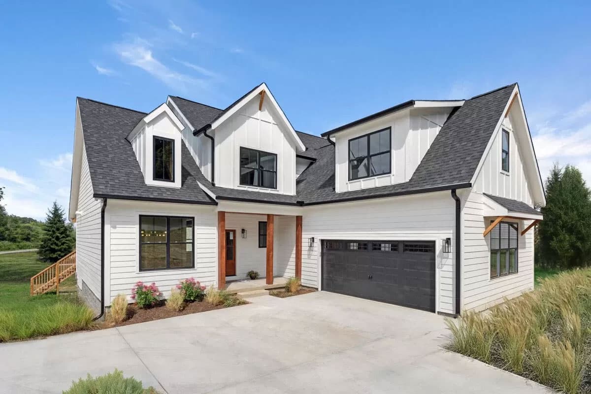 House plan exterior. Two-story Modern Farmhouse with gables, dormers, and a front-facing garage. Features a covered porch and dark roof.