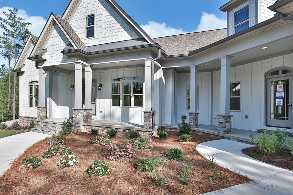 House plan exterior: Modern Farmhouse style, two stories, covered porch with stone-clad columns, gables, and board and batten siding.