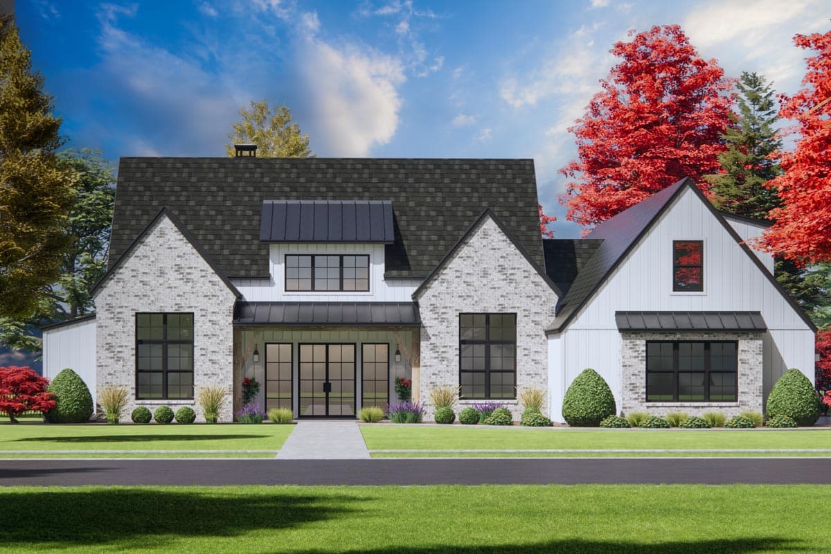 A modern farmhouse with a white exterior, dark trim, and a black roof. Brick accents adorn the facade, with colorful trees framing the home.