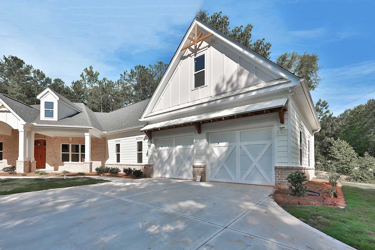 Modern Farmhouse house plan exterior with a side-entry three-car garage, prominent gables, and a covered front porch with brick accents.