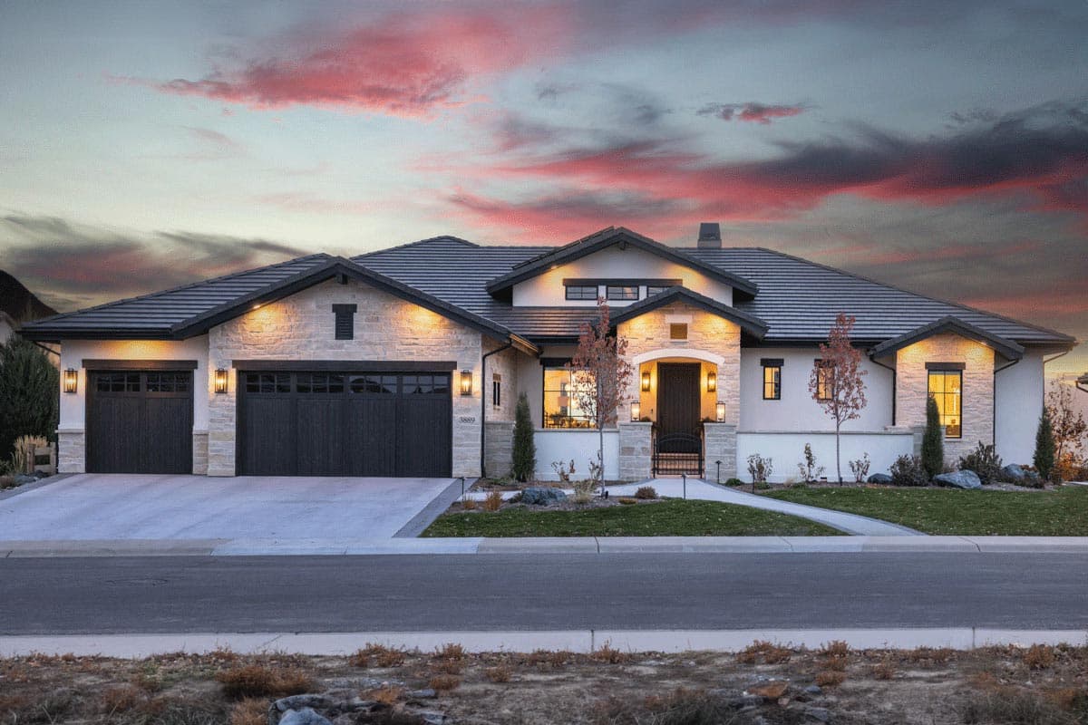 House plan exterior. Two-story Modern house with a stone and stucco facade, three-car garage, and multiple gables. Entry has arched portico.