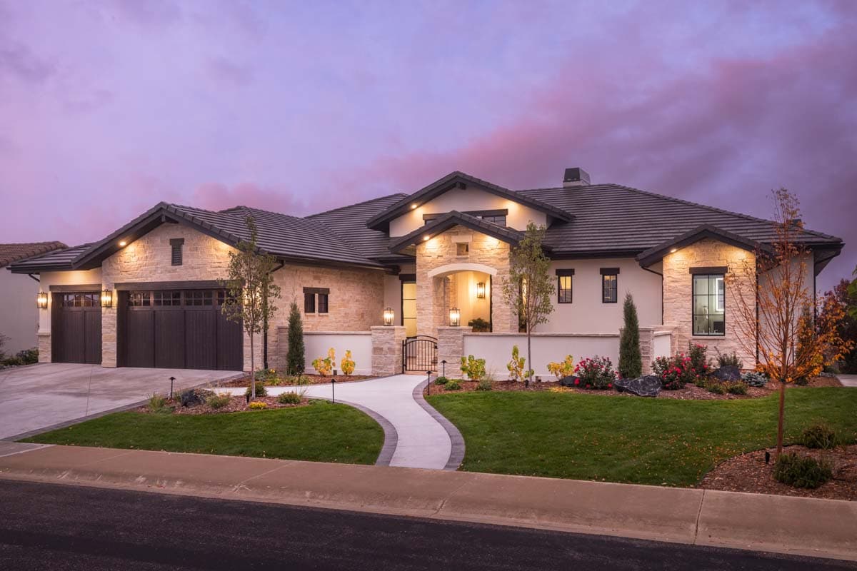 Modern home exterior with stone accents, tile roof, arched entryway, and a three-car garage.