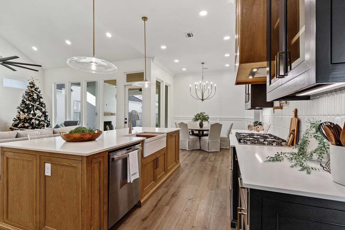 Open-concept kitchen with island, farmhouse sink, dining area, and adjacent living room with Christmas tree.