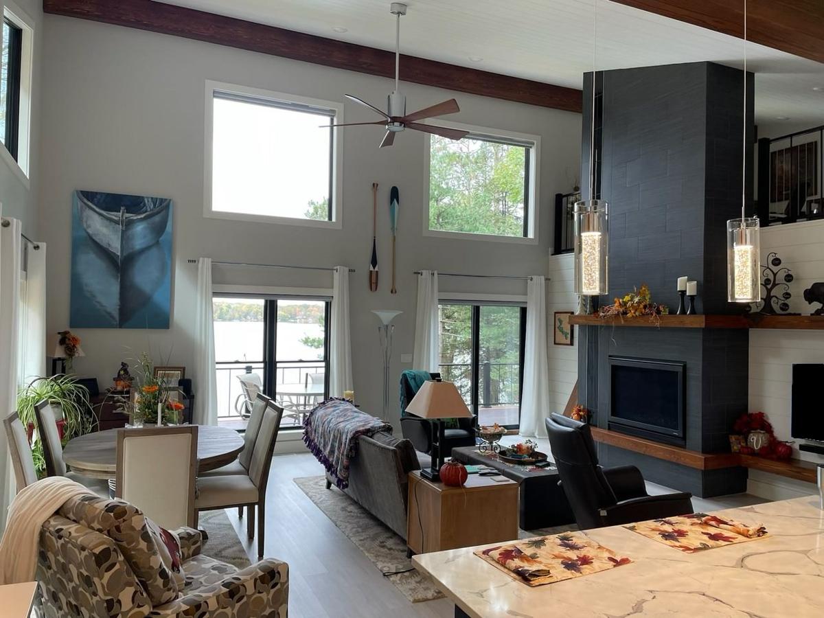 Great room with vaulted ceiling, large windows, stone fireplace, and dining area.
