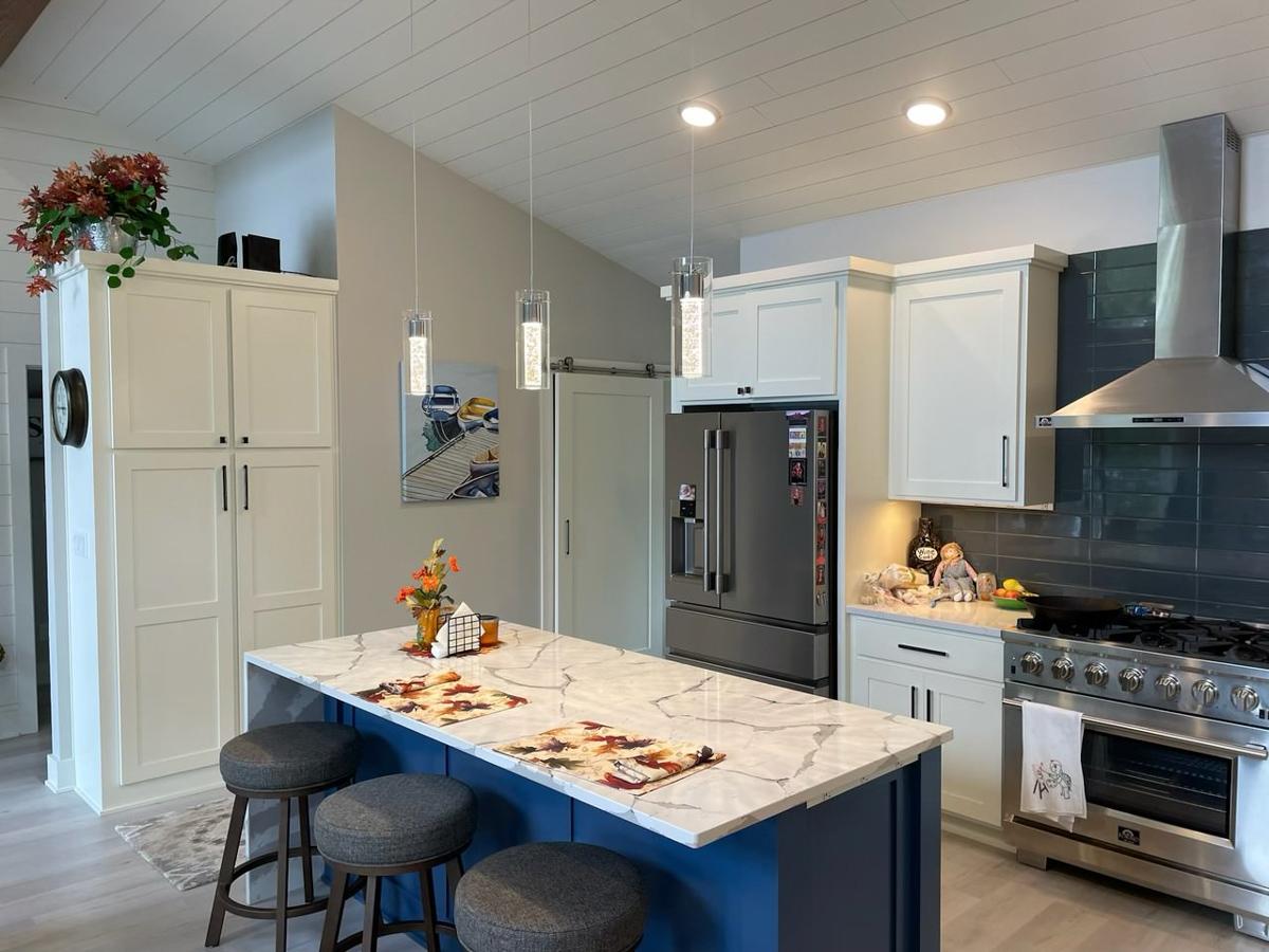Kitchen with island, white cabinetry, stainless steel range and hood, and vaulted shiplap ceiling.