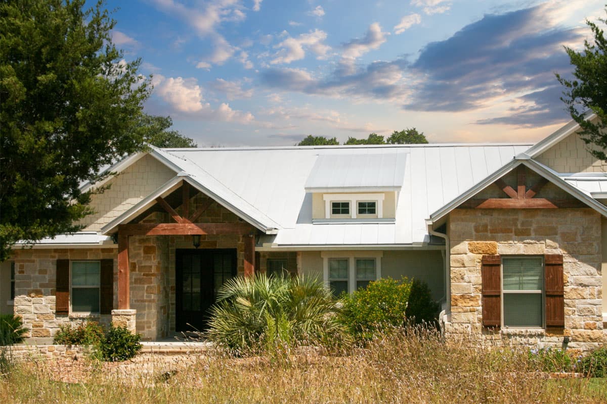 House plan exterior with stone veneer, metal roof, and exposed timber-framed entry porch with gables and dormer.