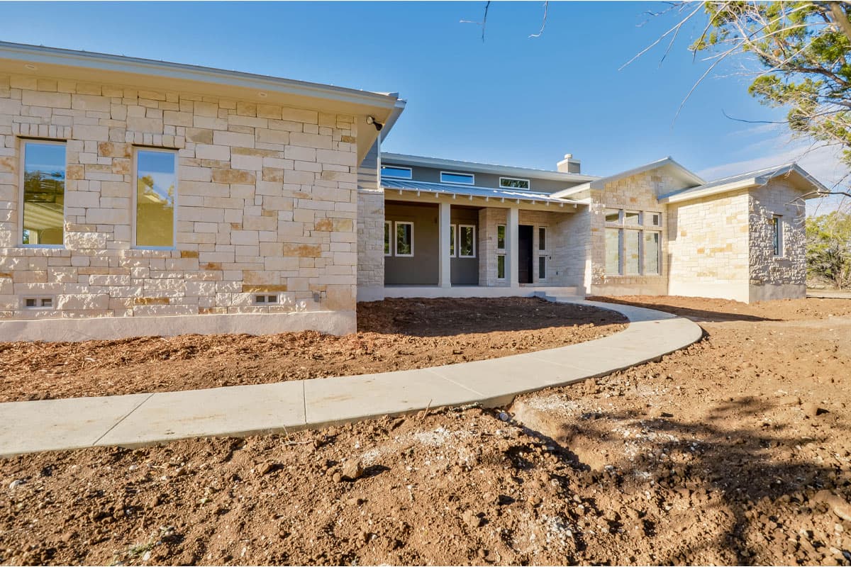 House plan exterior: Modern style with stone facade, covered entry porch supported by columns, and metal roofline.