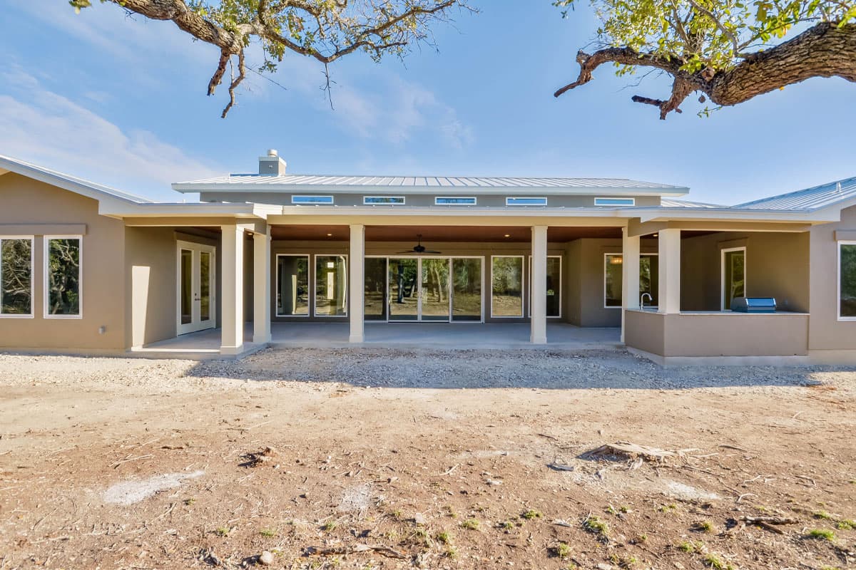 House plan exterior view of a single-story Modern style home with a covered patio, large windows, and a metal roof.