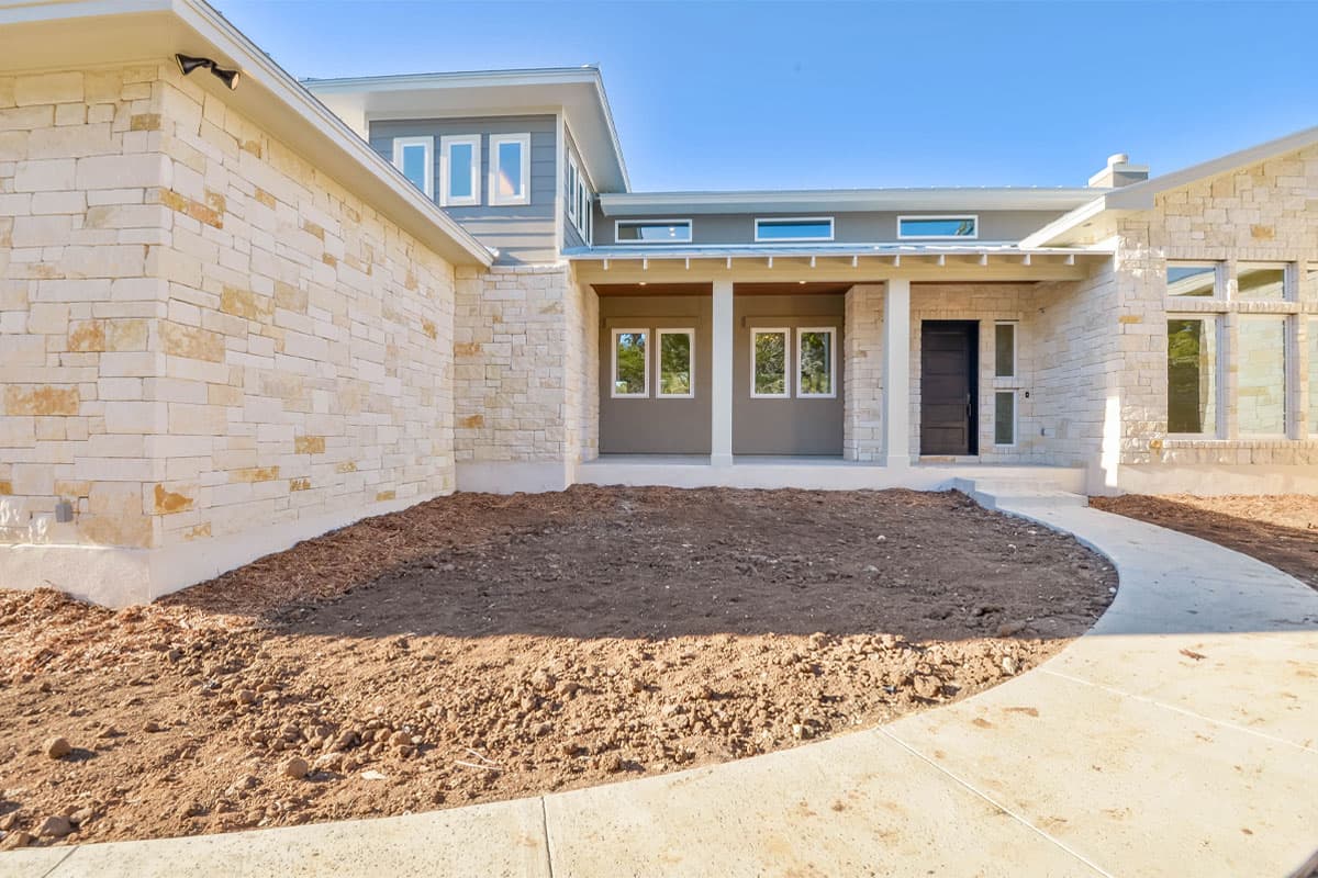 House plan exterior with stacked stone facade, covered entryway with columns, and multiple window styles.