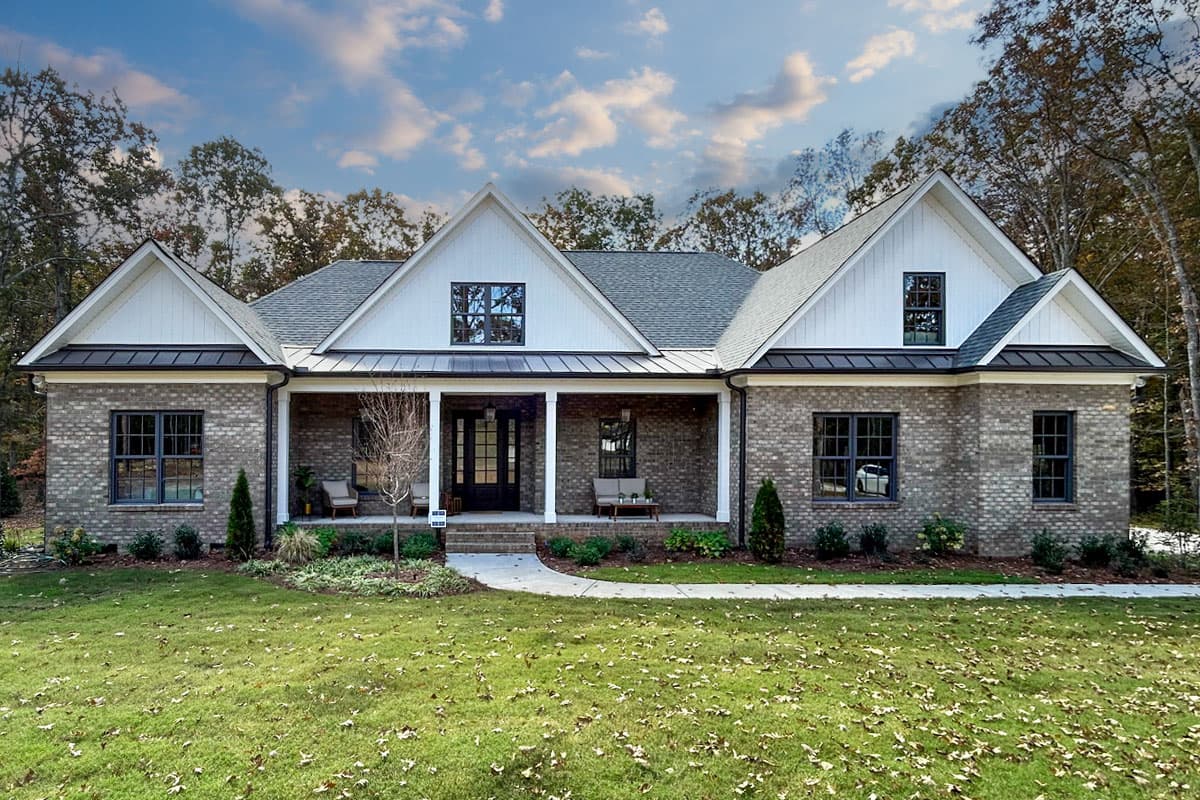 House plan exterior. Modern Farmhouse style, one-story. Features include gabled roof, covered porch, and brick facade.