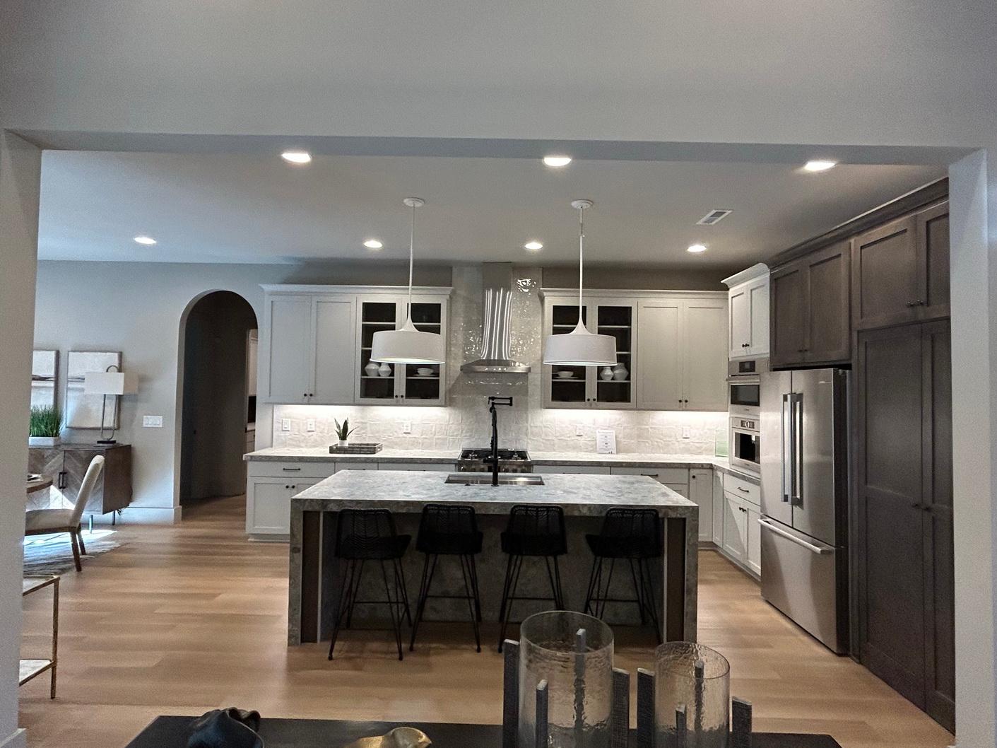 Kitchen with island, white shaker cabinets, stainless steel appliances, and an arched doorway to an adjacent room.