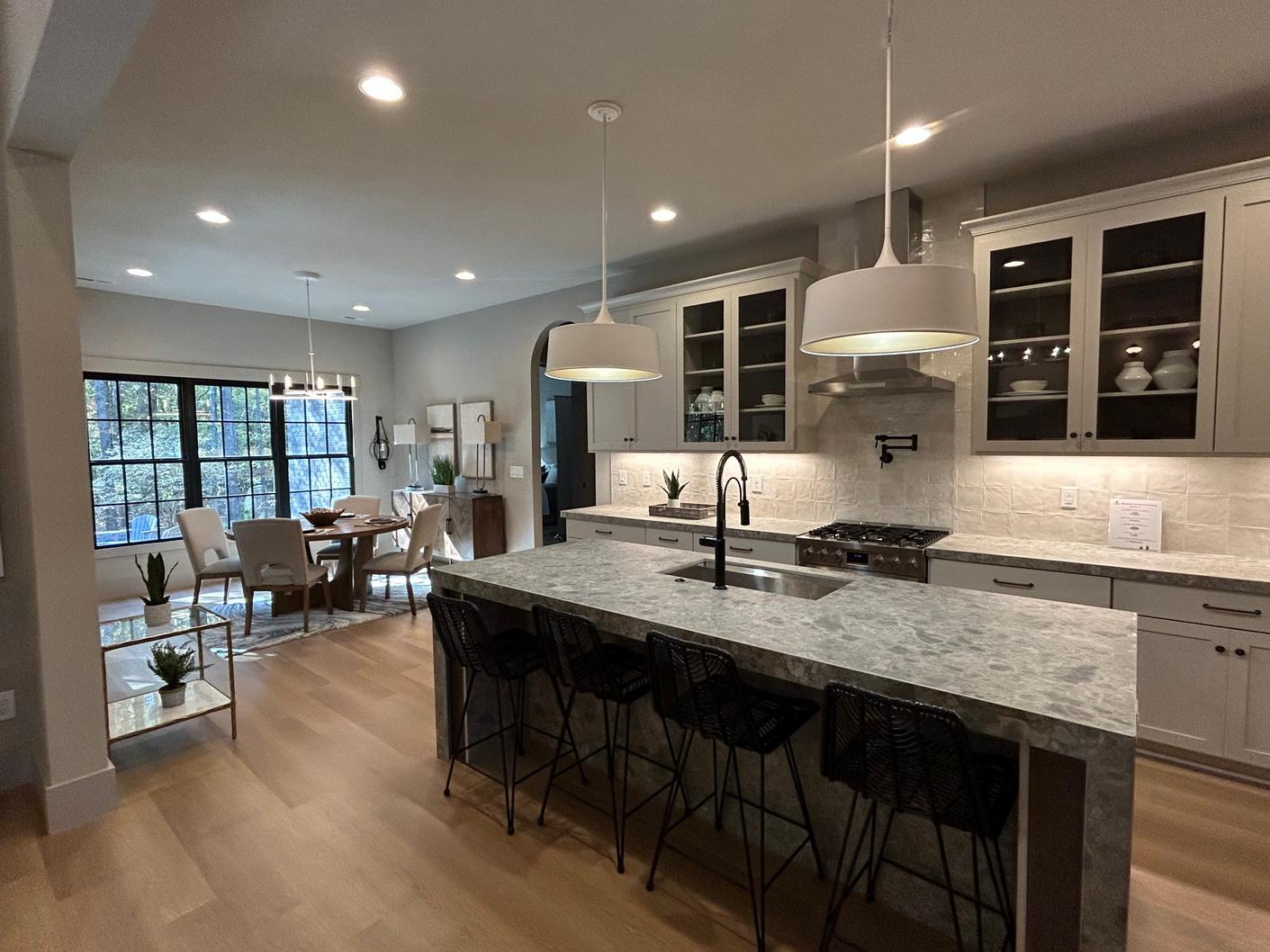 Open concept kitchen with large island, gas range, and dining area with bay window.