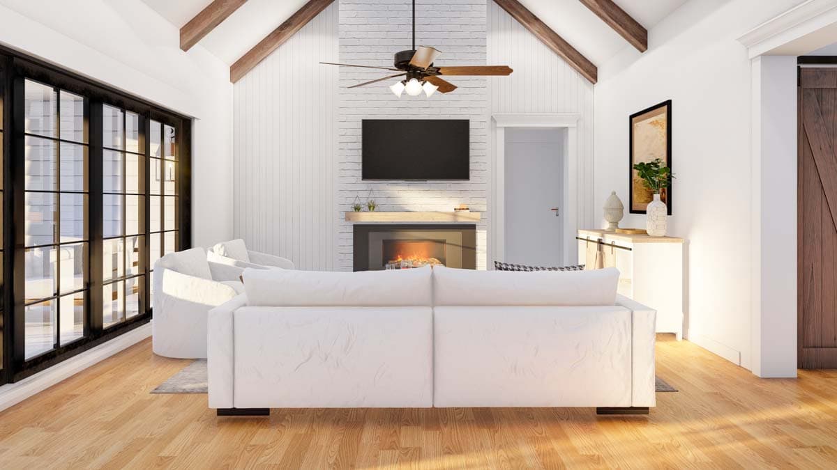 Great room with vaulted ceiling, exposed beams, brick fireplace, and large windows.