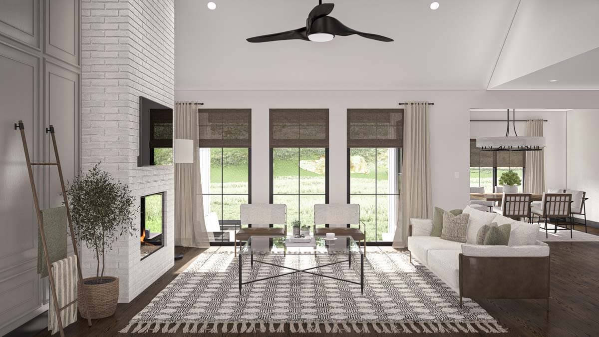 Modern living room interior with vaulted ceiling, white brick fireplace, large windows, and adjacent dining area.