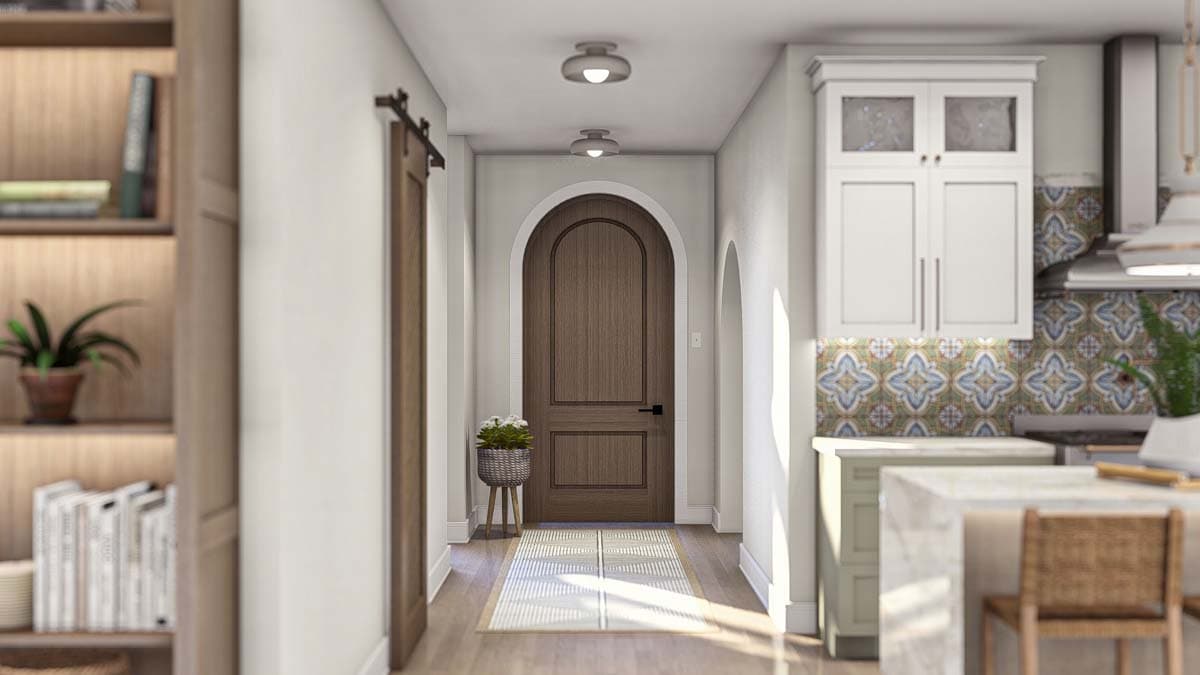 Interior view of a hallway with a wooden arched door, barn door, built-in shelving, and adjacent kitchen area.