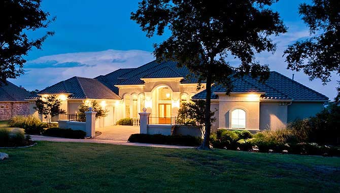 Mediterranean style house plan exterior with arched entryway, multiple gables, and a tiled roof.
