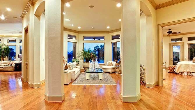 Interior view of a living area with arched doorways, a bay window, and view into a bedroom.