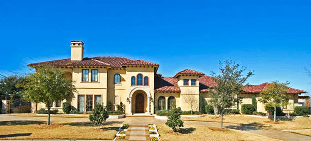 House plan exterior. Two-story Mediterranean-style house with arched entry, red tile roof, and multiple dormers and chimneys.