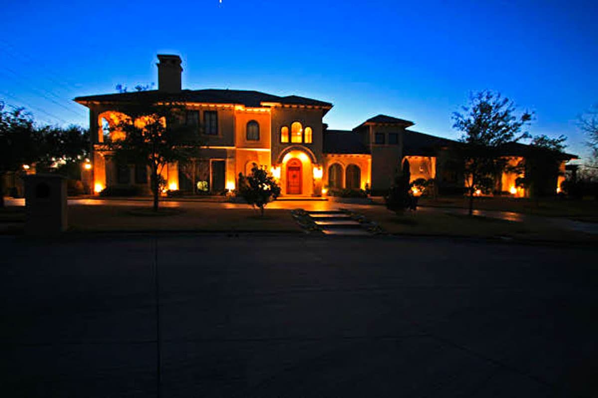 House plan exterior, two stories, stucco facade, arched windows, central arched entrance, large chimney, covered loggias.