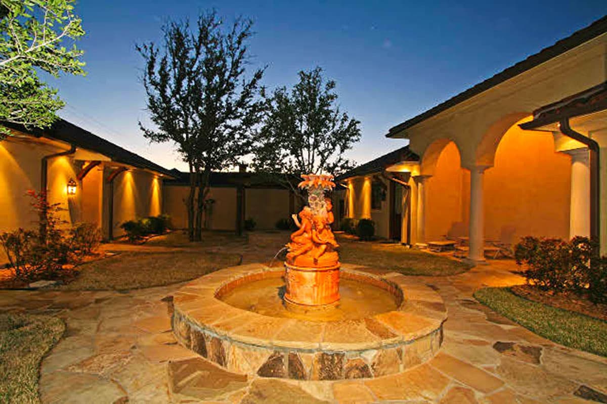 House plan exterior with a courtyard, fountain, arched loggia, and stucco walls. Mediterranean style.
