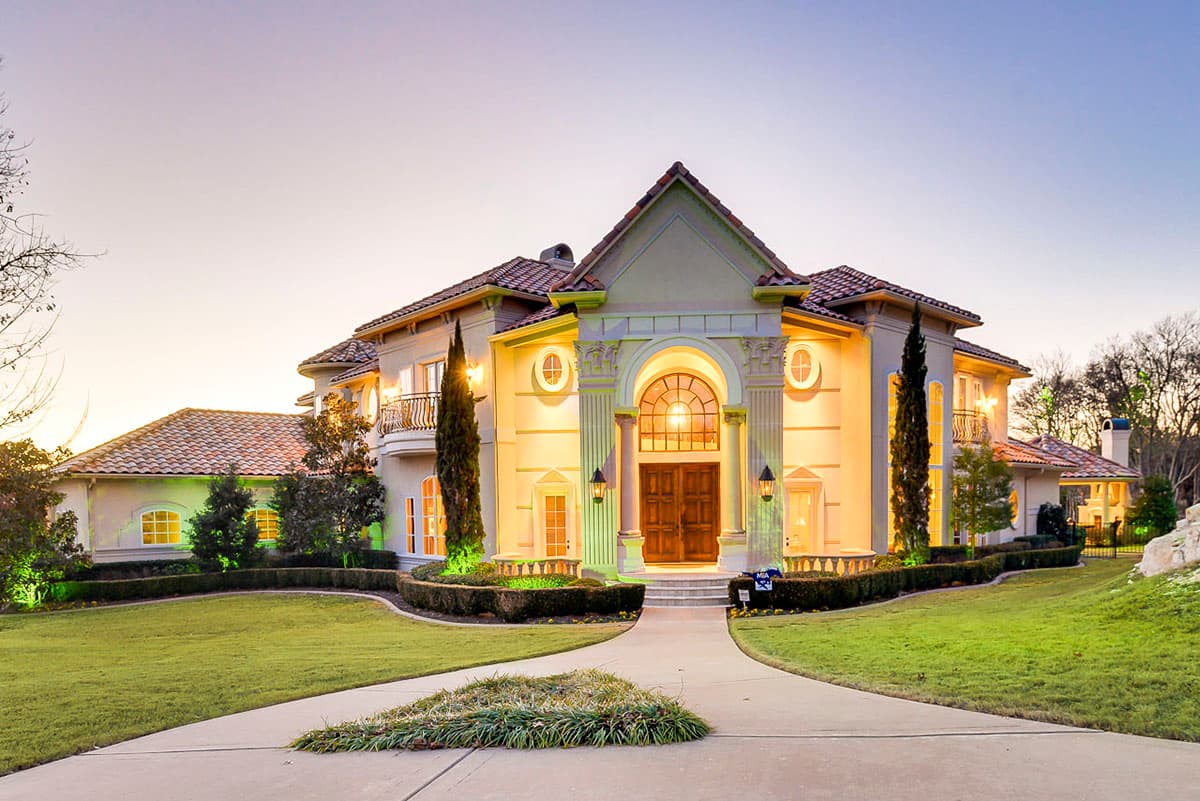 House plan exterior. Two-story Mediterranean-style home with arched entry, columns, and tile roof. Features include balconies and dormers.
