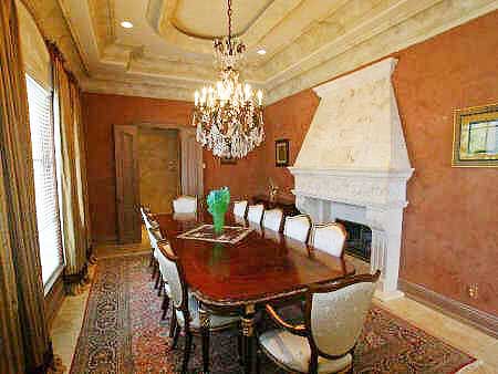 Dining room with ornate fireplace, large chandelier, and a long dining table set for ten.