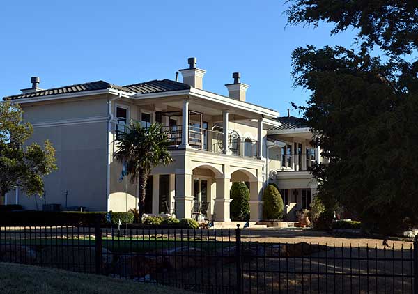 Two-story house plan exterior with arched entryway, covered balconies, tile roof, and multiple chimneys.