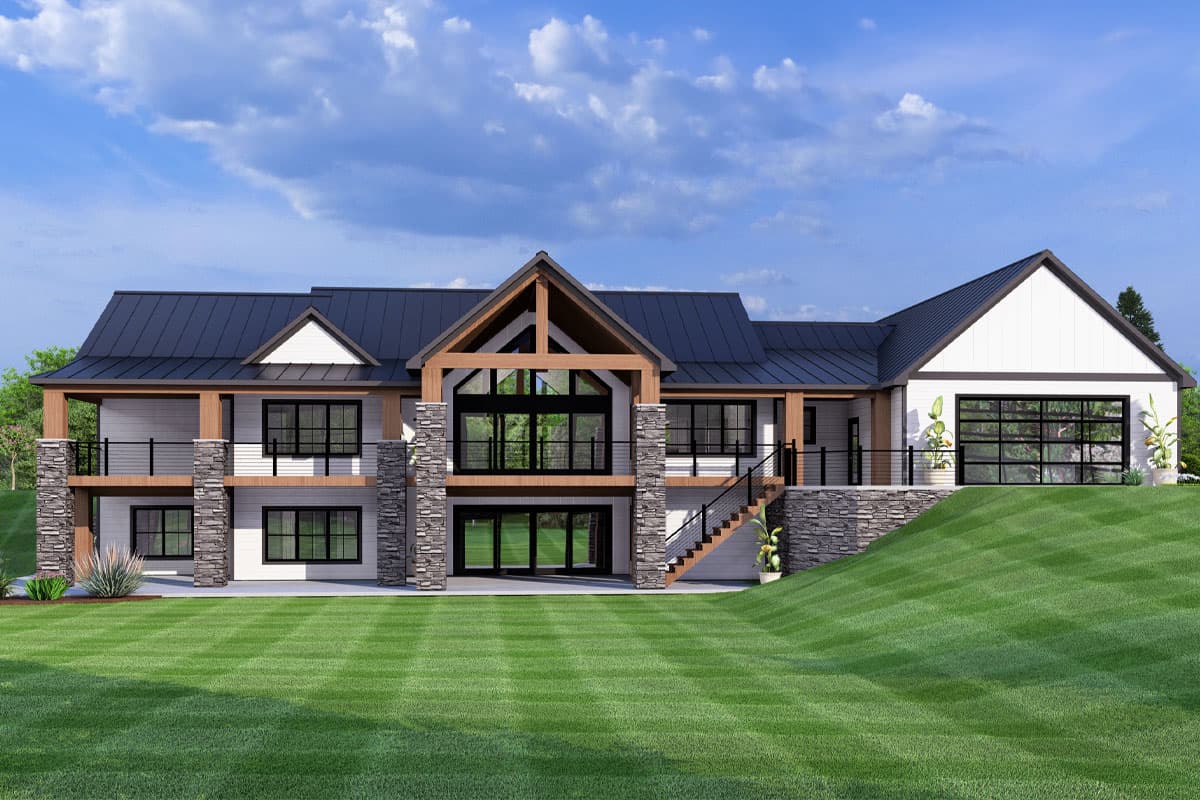 A modern, two-story house with a black roof, stone columns, and large windows. The house sits on a green lawn against a blue sky.