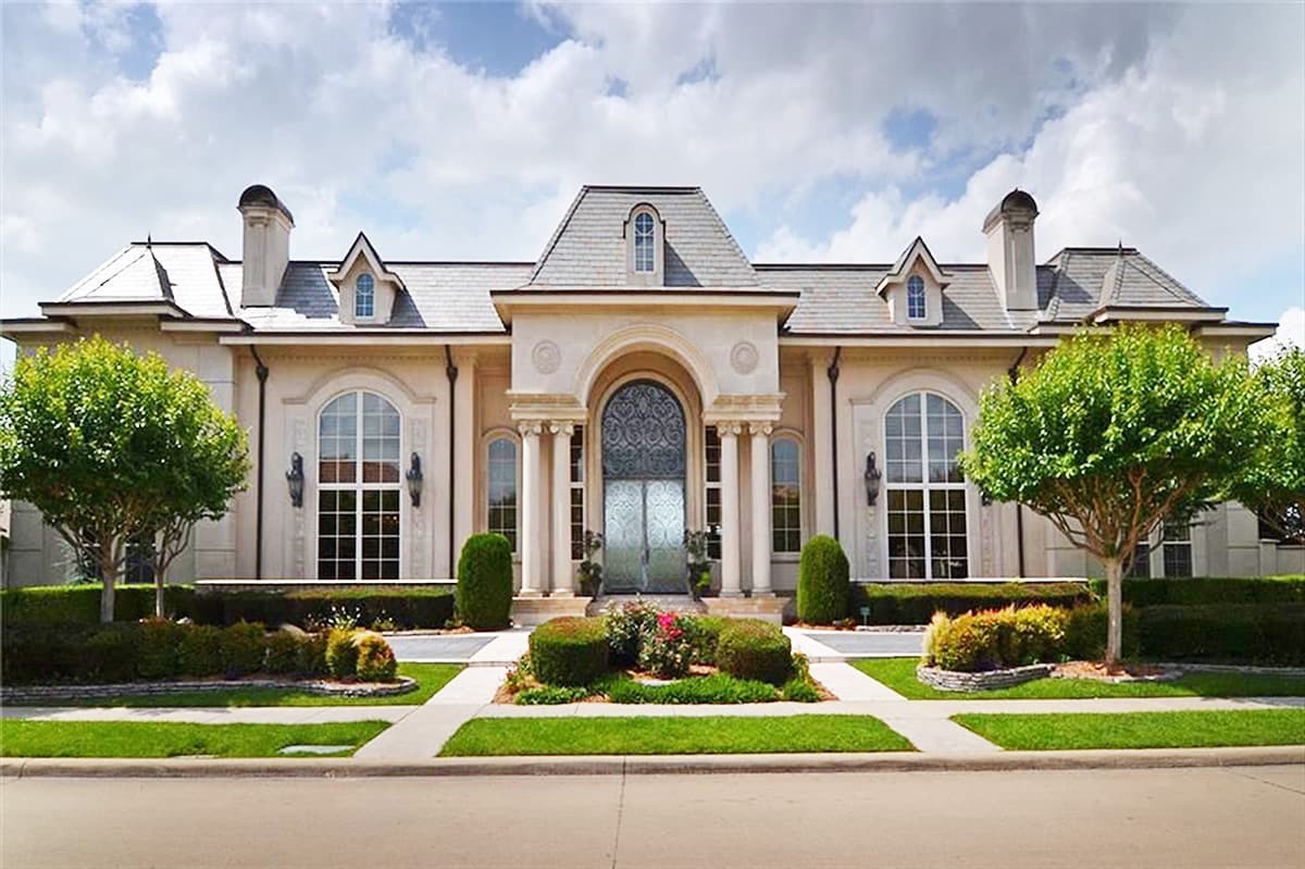 House plan exterior: French Provincial style, two stories, mansard roof, arched windows, central pediment entrance with ornate double doors.