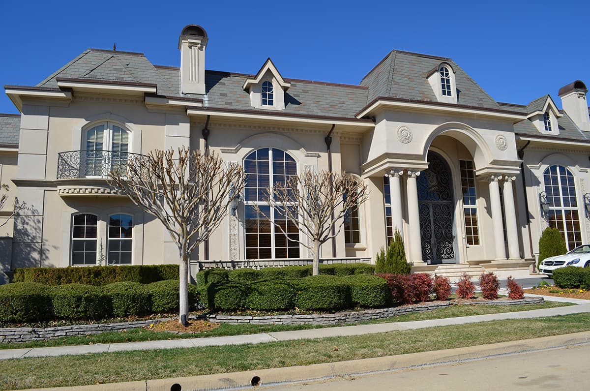 House plan exterior featuring a grand arched entryway, multiple dormers, arched windows, and a Juliet balcony with ornate railing.