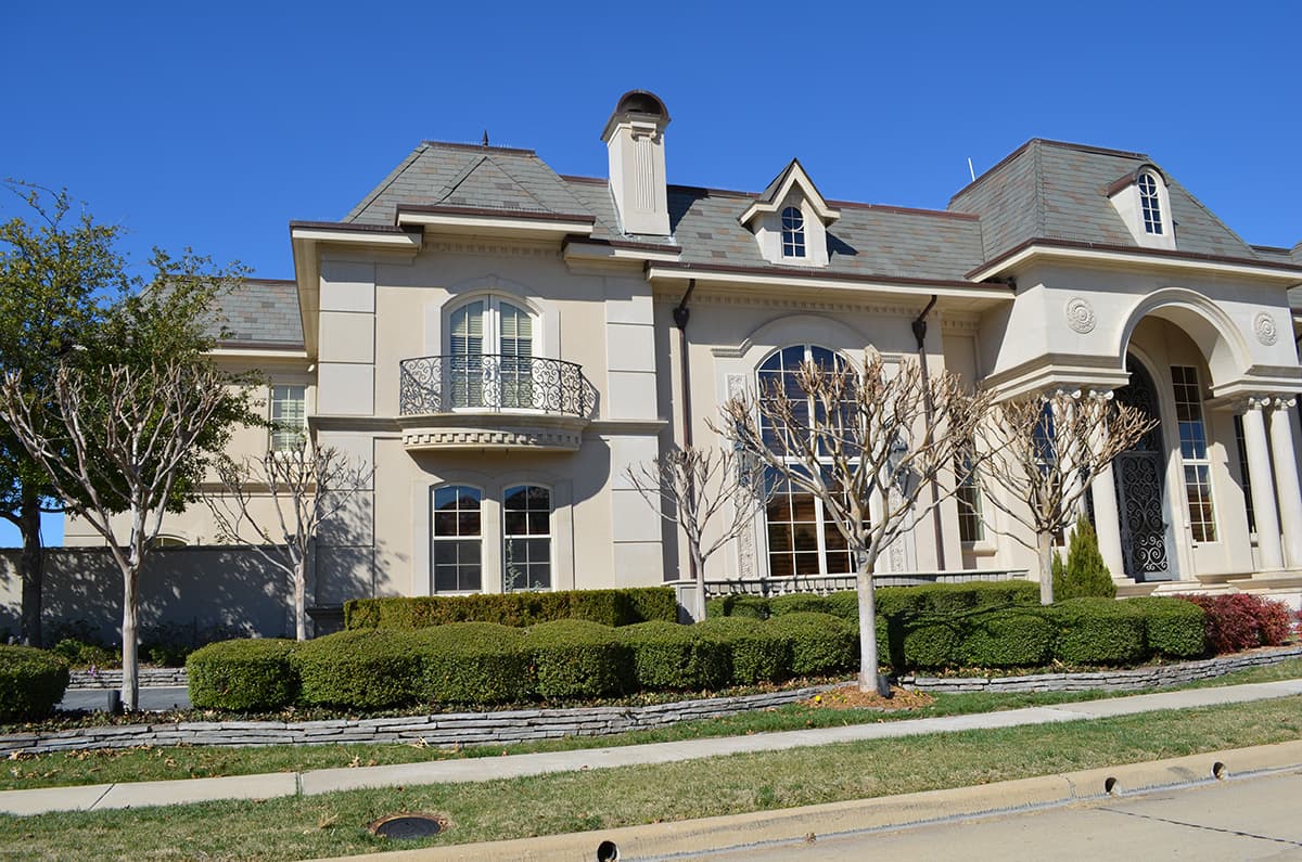 House plan exterior shows a multi-story stone mansion with arched windows, a Juliet balcony, and a slate roof.
