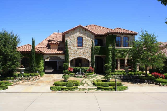 House plan exterior: Stone and stucco two-story Mediterranean style home with arched entryway and tile roof.
