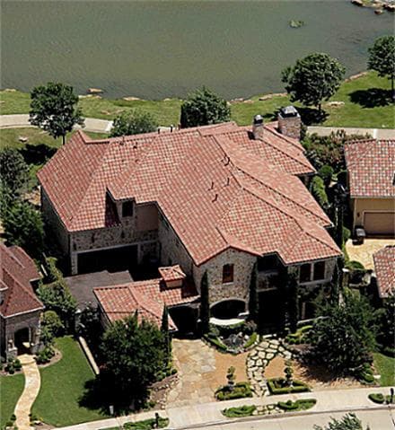House plan exterior showing a multi-story residence with a red tile roof, stone facade, and attached garage.