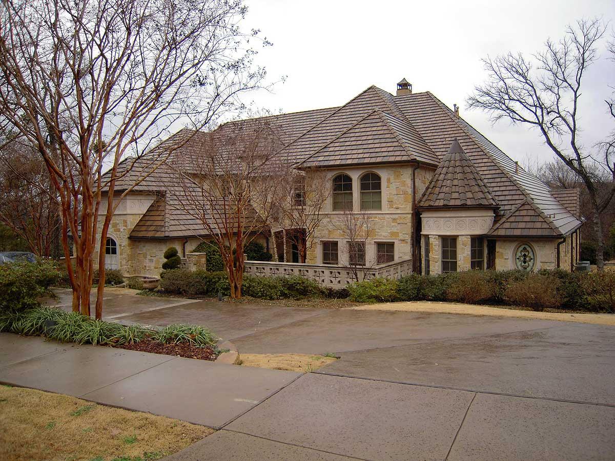 House plan exterior: two-story stone home with complex rooflines, arched windows, and a conical turret.