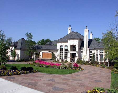 House plan exterior: two-story residence with arched entryway, multiple gables, prominent chimneys, and attached garage.