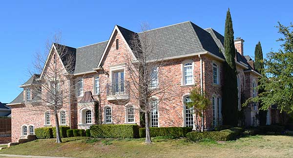 French Provincial house plan exterior with brick facade, multiple gables, arched windows, and a central Juliet balcony.
