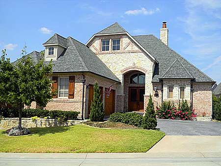 House plan exterior: Two-story brick home with arched entry, dormers, multiple gables, and attached garage.