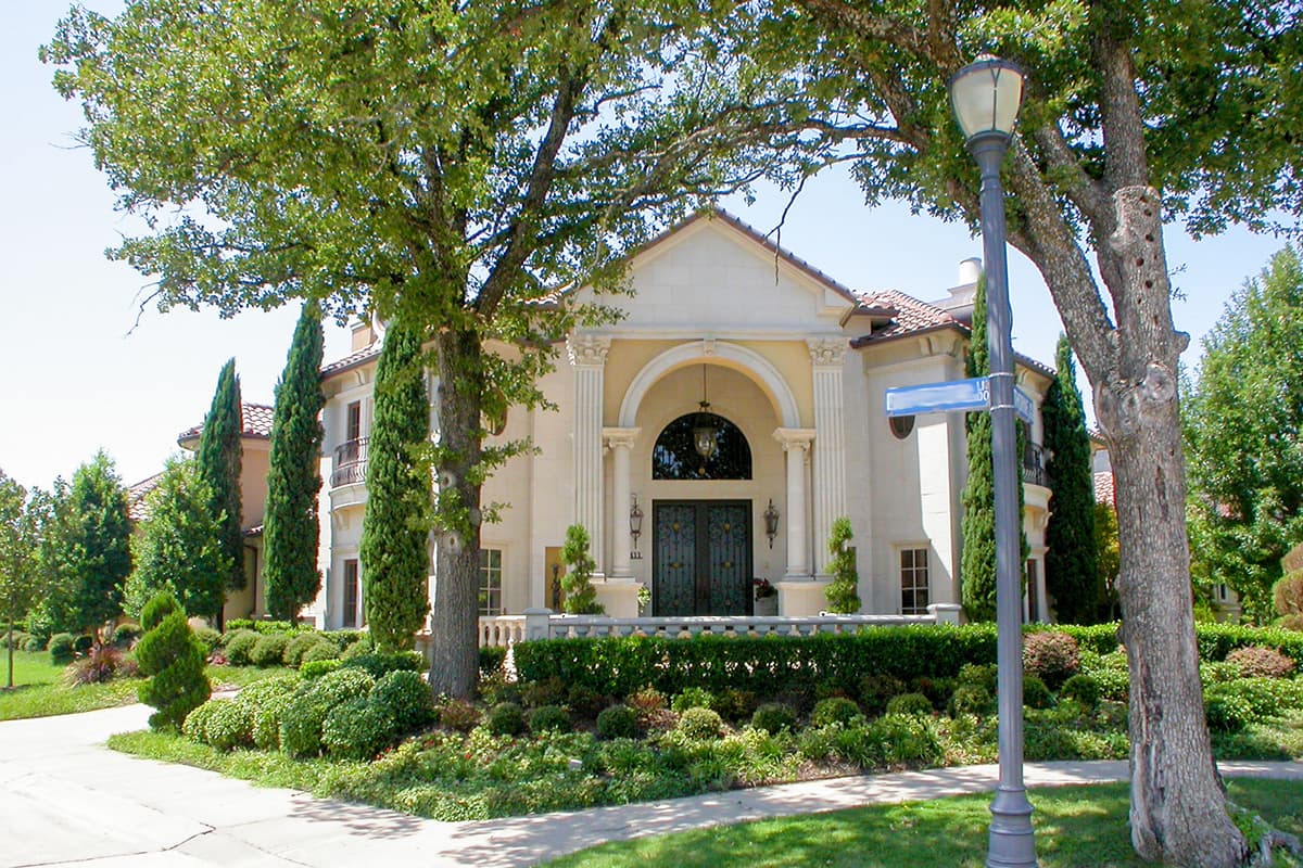 House plan exterior. Tall arched entryway with double doors, classical columns, balustrade, and symmetrical facade.