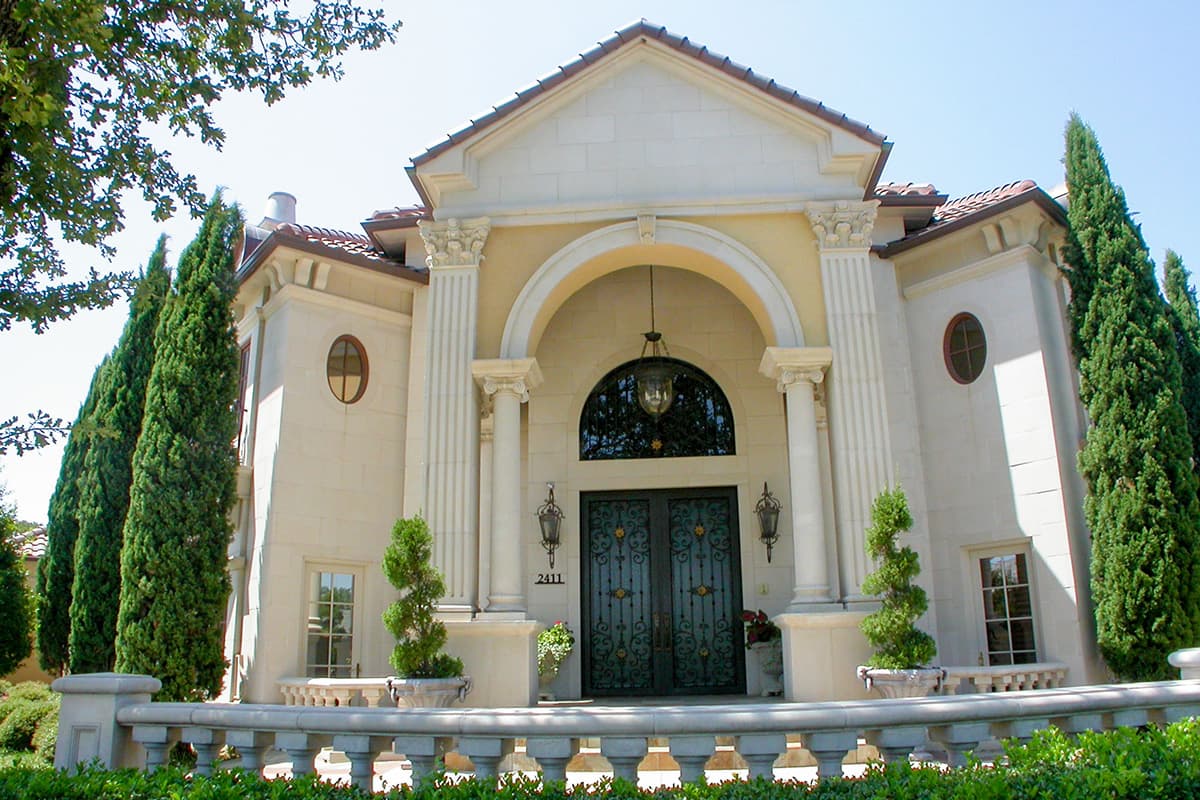House plan exterior: Large arched entryway with double doors, decorative lanterns, columns, and ornamental balustrade.