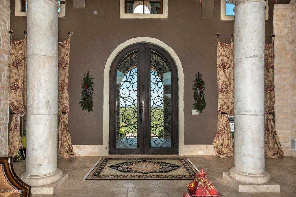 House plan interior: Arched double doors with wrought iron, flanking fluted columns, patterned curtains, and tiled floor.