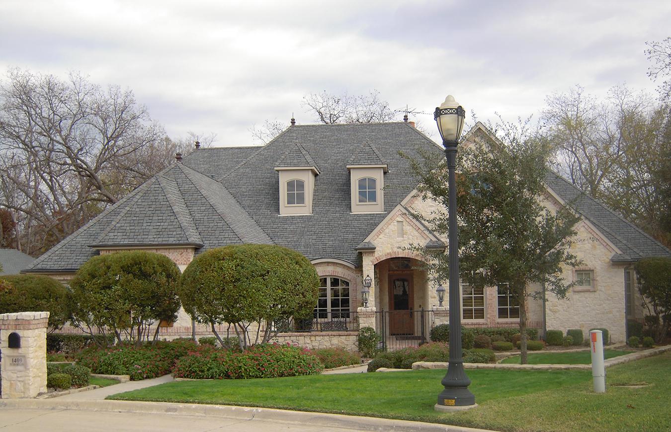 House plan exterior: French Country style, two stories, arched entry, dormers, and stone facade.