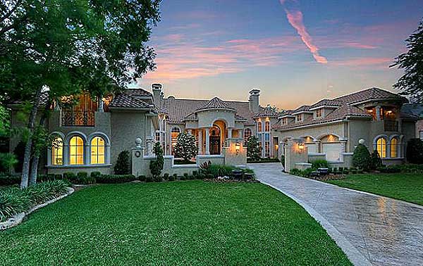 Mediterranean-style house plan exterior with stucco walls, arched windows, tile roof, and a prominent arched entryway.
