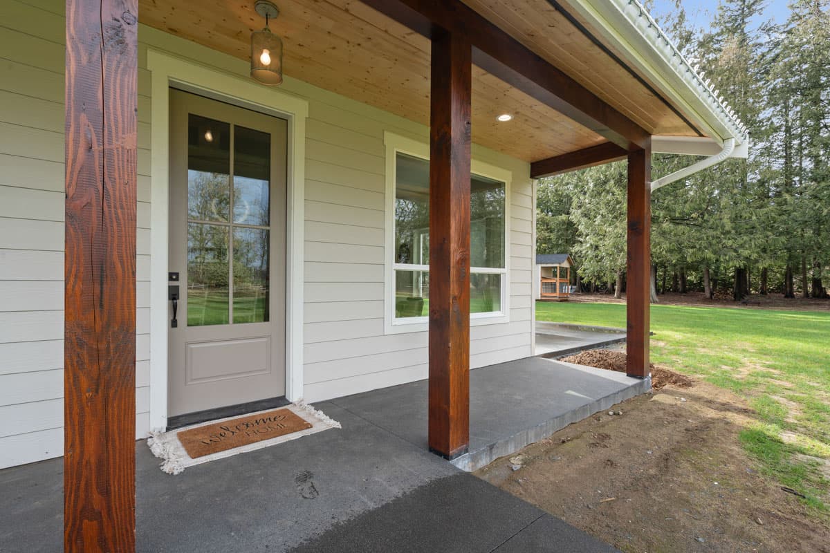 House plan exterior with wood-accented covered porch, door with glass panes, and horizontal siding.