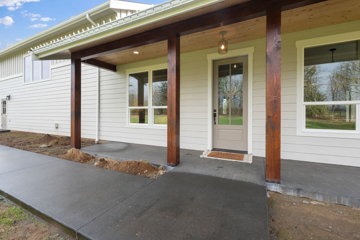 House plan exterior with covered entry, wood columns, large windows, and siding.