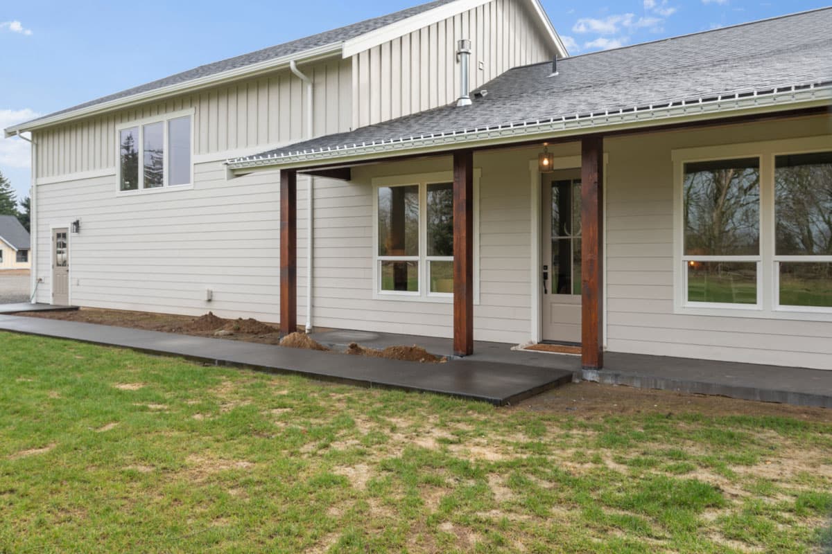 House plan exterior: Modern Farmhouse style, two stories, featuring a covered porch with wooden posts, gable roof, and vertical siding.