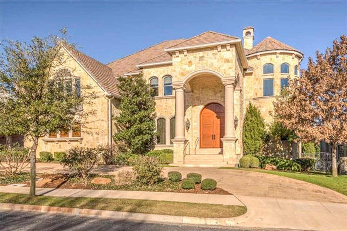 House plan exterior. Two-story home with arched entry, engaged columns, a turret, and multiple rooflines.